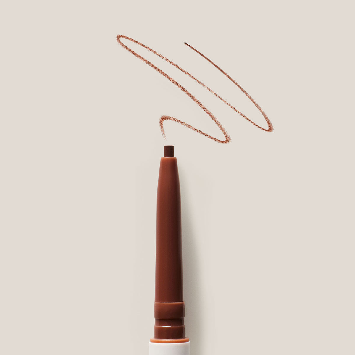 A close up of ILIA's Brow Pencil with a swatch of the shade on a light background.