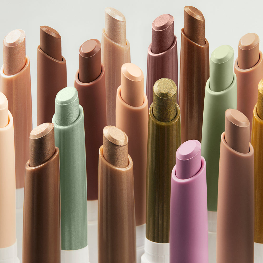 An assortment of shades in eye stylus eyeshadow sticks standing up against a light grey background.