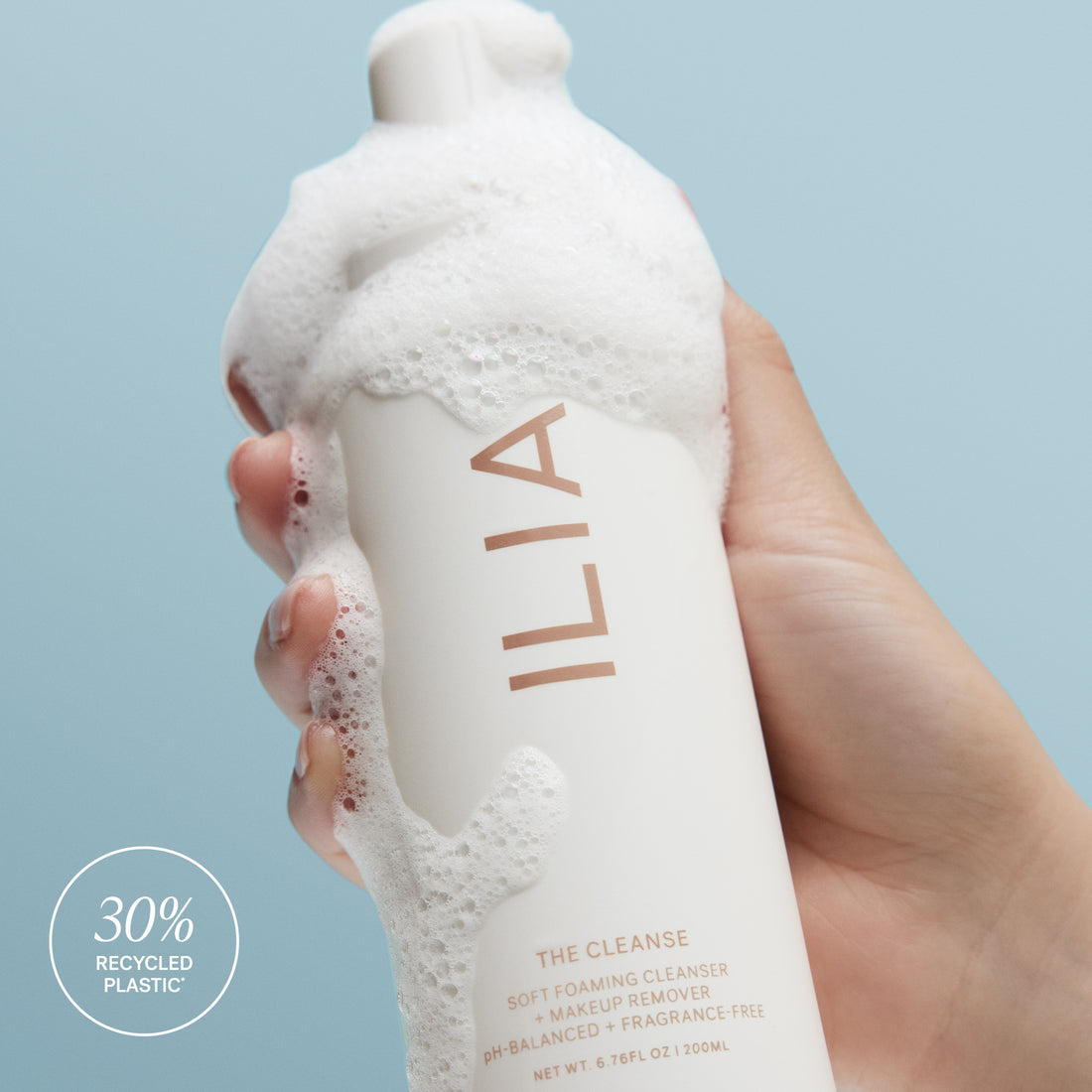 ILIA's the Cleanse being held in hand with foaming bubbles along the side. 30% of the bottle is Recycled Plastic.